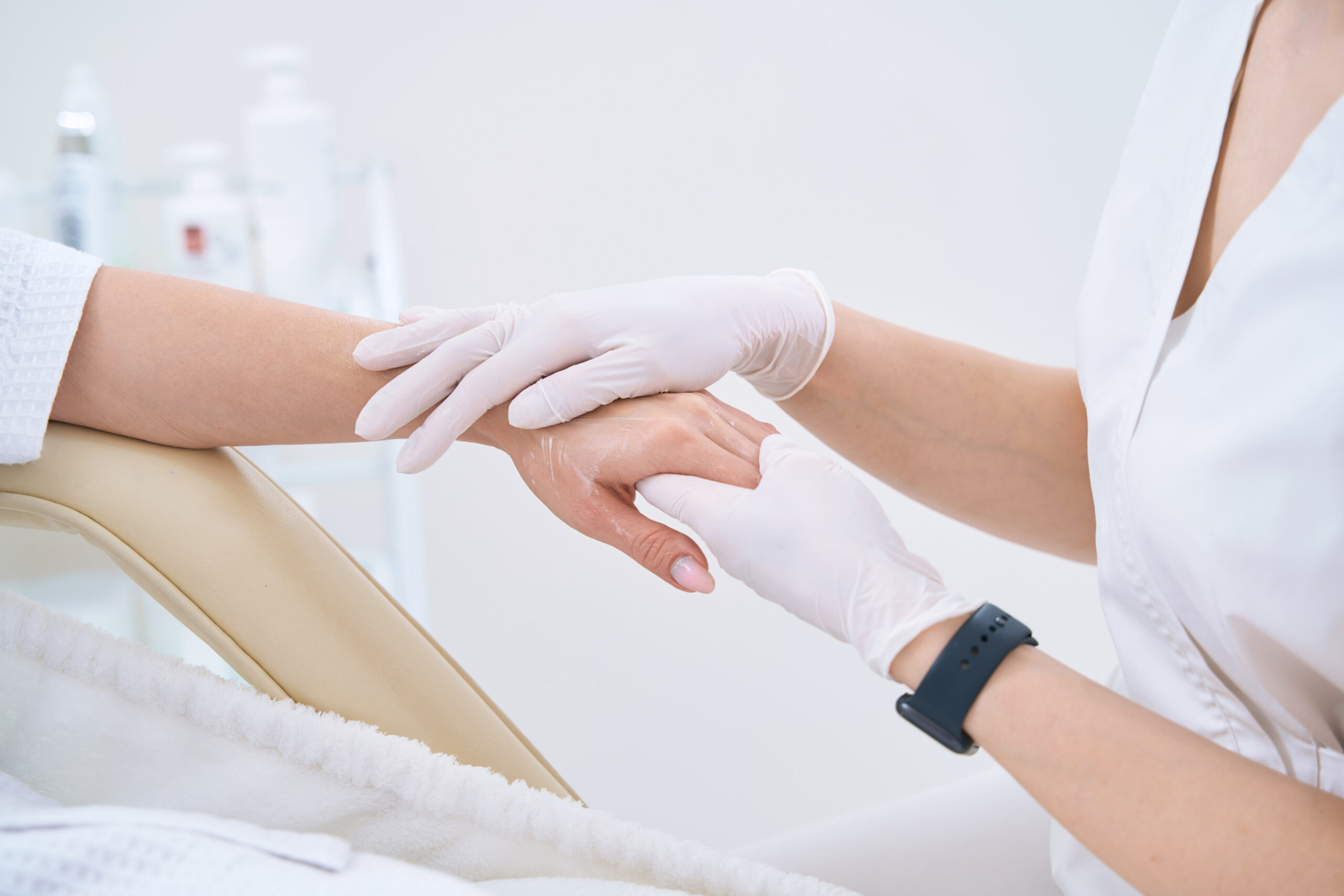 Close-up beautician doing hand massage in white gloves for lady